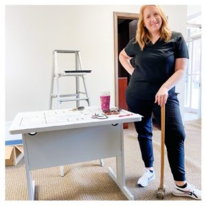Photo shows Dr. Hornberger, sledgehammer in hand, in the old bank building that will become her office