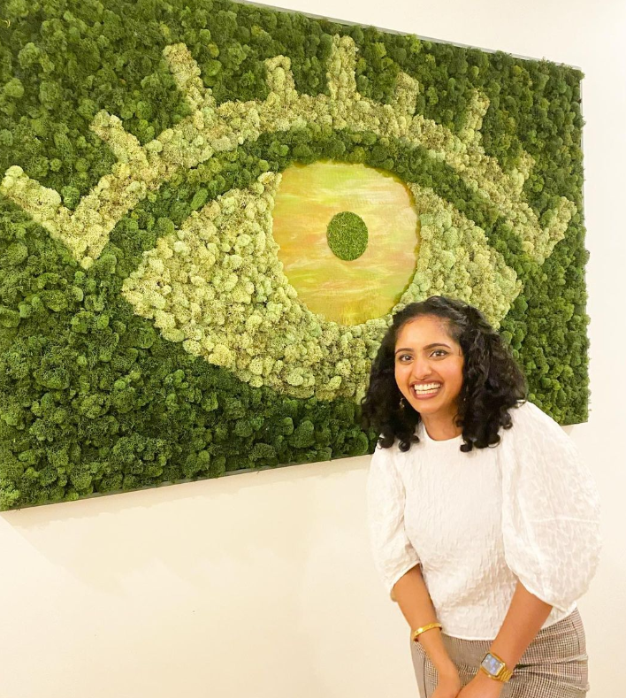 Dr. Vazhappilly posing in front of an eye mural
