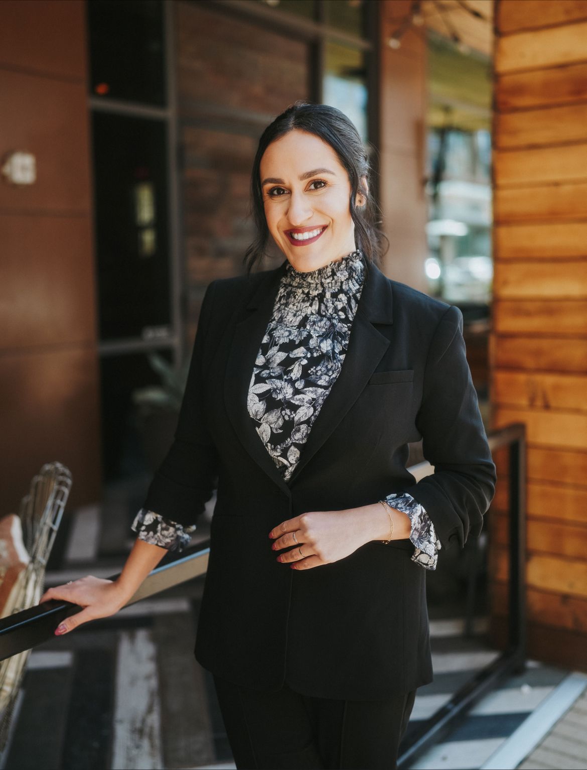 A photo of Dr. Foroutan, wearing a black and white floral blouse and a buttoned black blazer. 