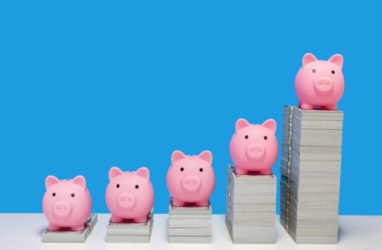 Pink piggy banks on ascending stacks of paper currency