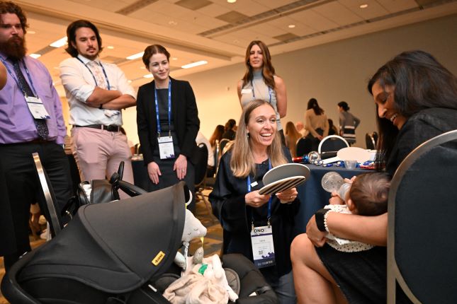 photo shows young optometrist engaging with an infant on mom's lap - with four students watching. This is infantsee program training. 