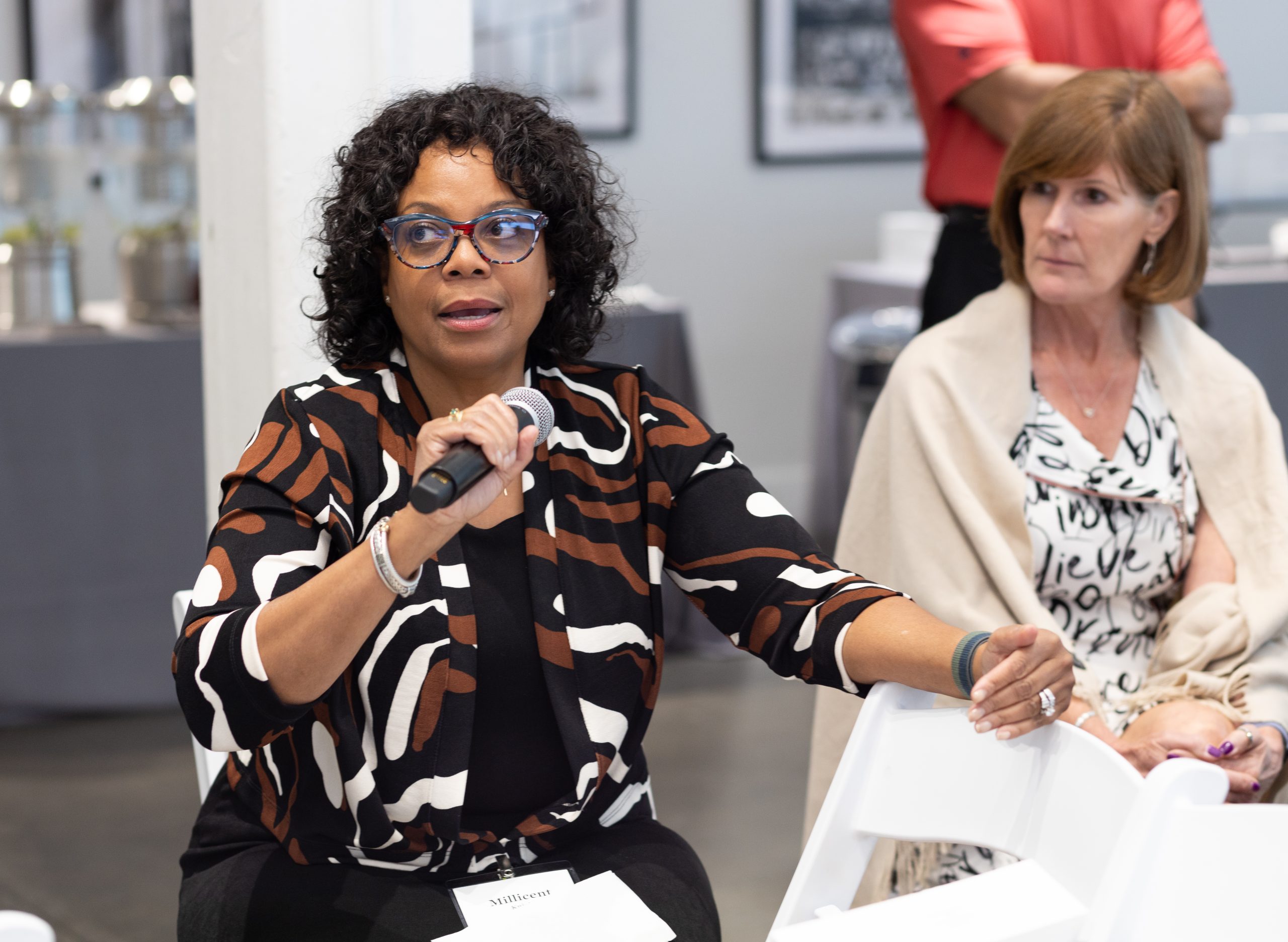 two women at a meeting - woman at left, Dr. Millicent Knight, speaks into microphone at the industry collaborative