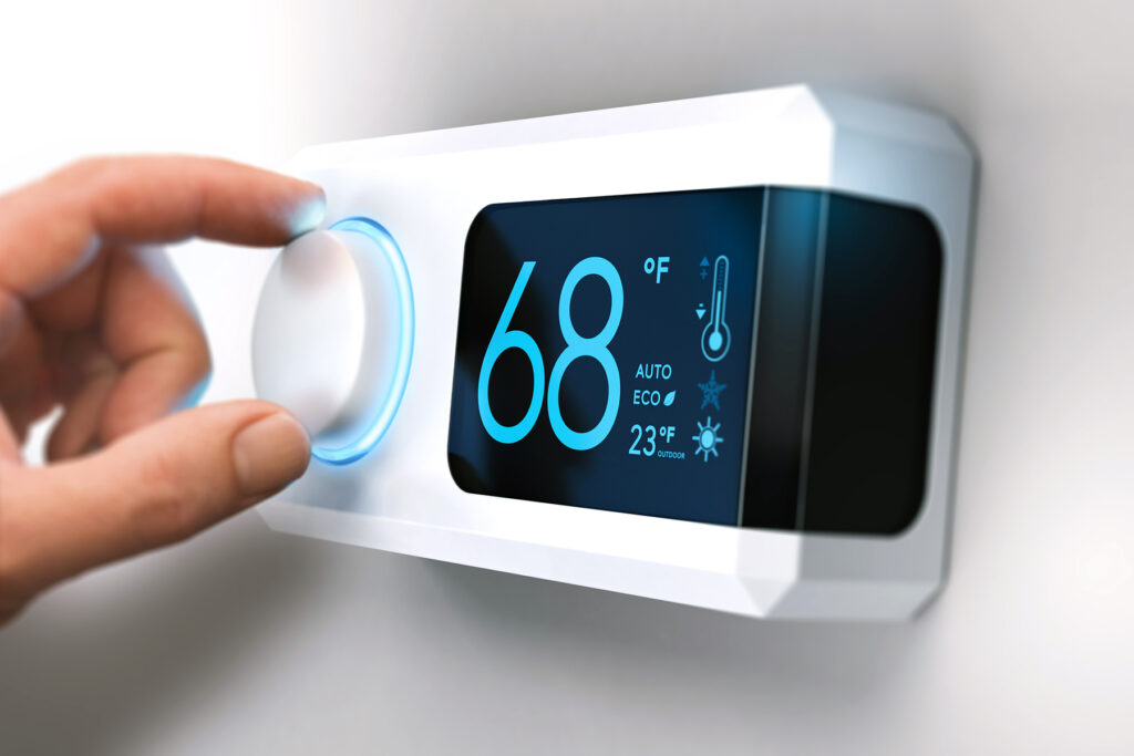 photo shows a hand adjusting a thermostat set at 68 degrees