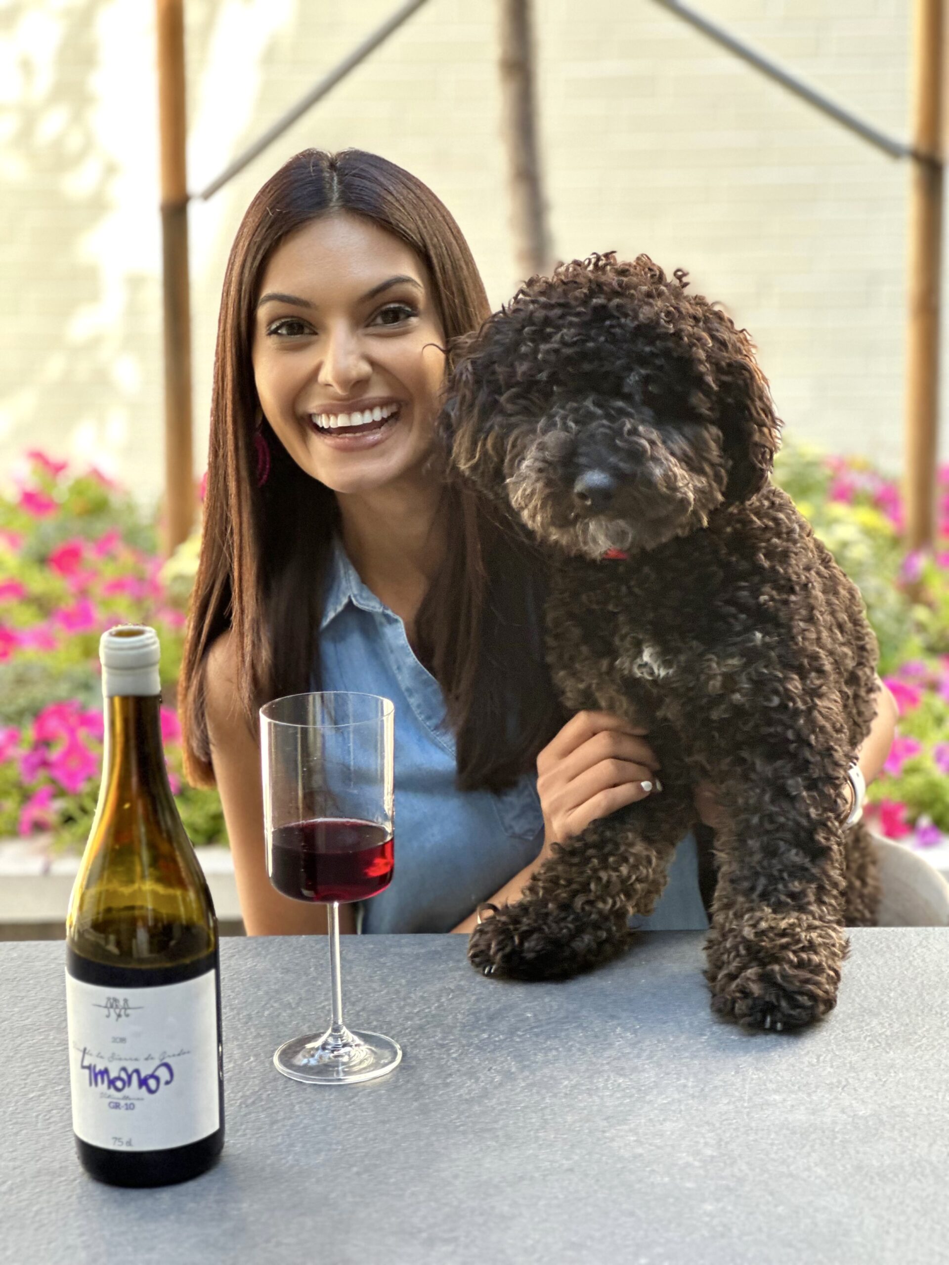 Dr. Virani with her dog Moose and a bottle and glass of red wine she recommends