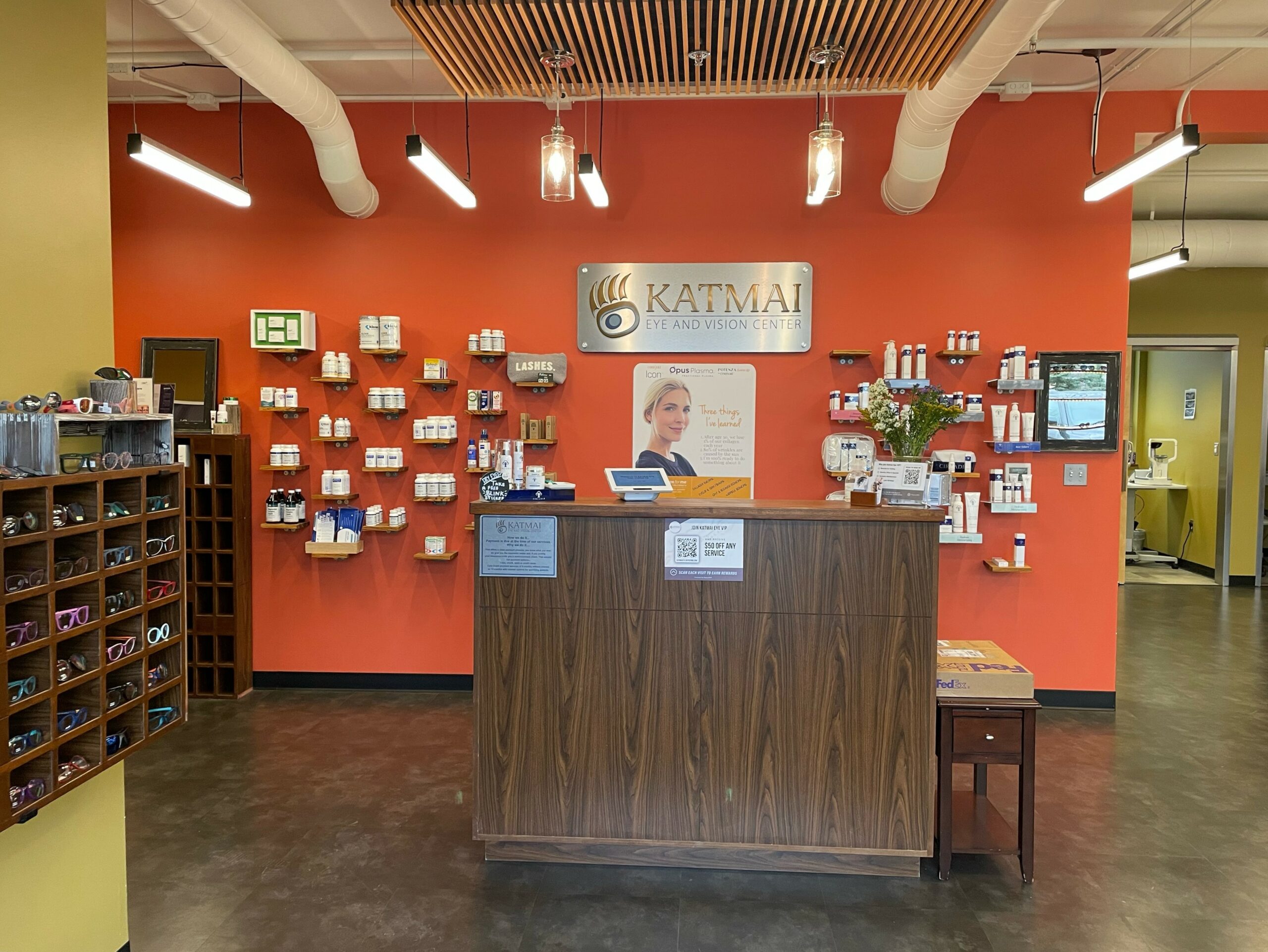 The front wooden kiosk in front of an orange wall with the Katmai logo and signage