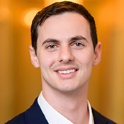 Andreas Zacharopoulos portrait against orange background. He's a recent top grad from 2019