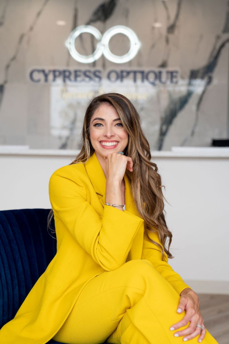 Dr. Celesta Ferreira in bright yellow suit in front of her Cypress Optique practice where she treats dry eye