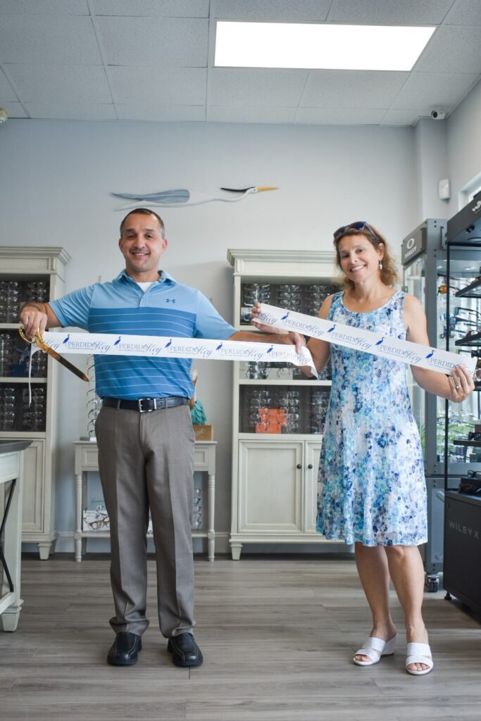 two doctors holding cut ribbon after grand opening
