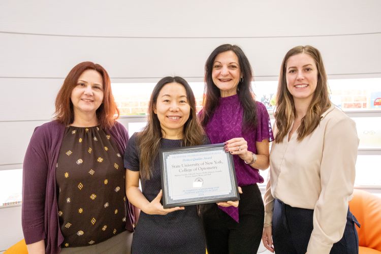 four women from a SUNY Optometry research team hold an award