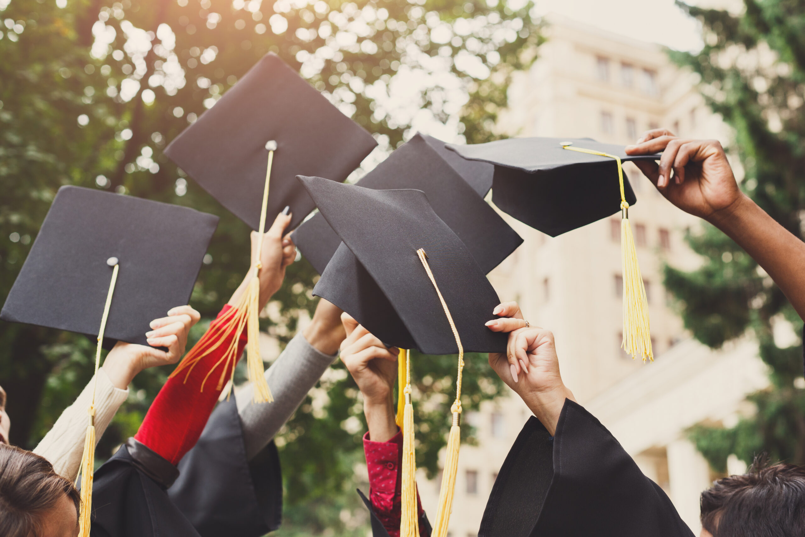 graduates holding up their mortarboards IS_180710_college_graduates_iStock-947295034.jpg